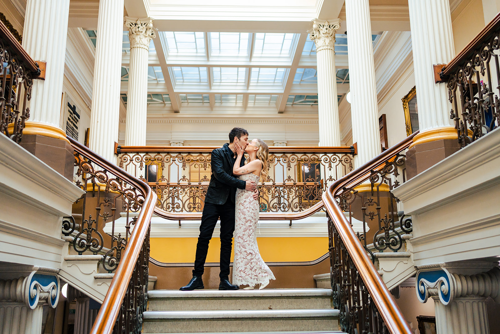 A bride and groom standing on the stairs of a building.