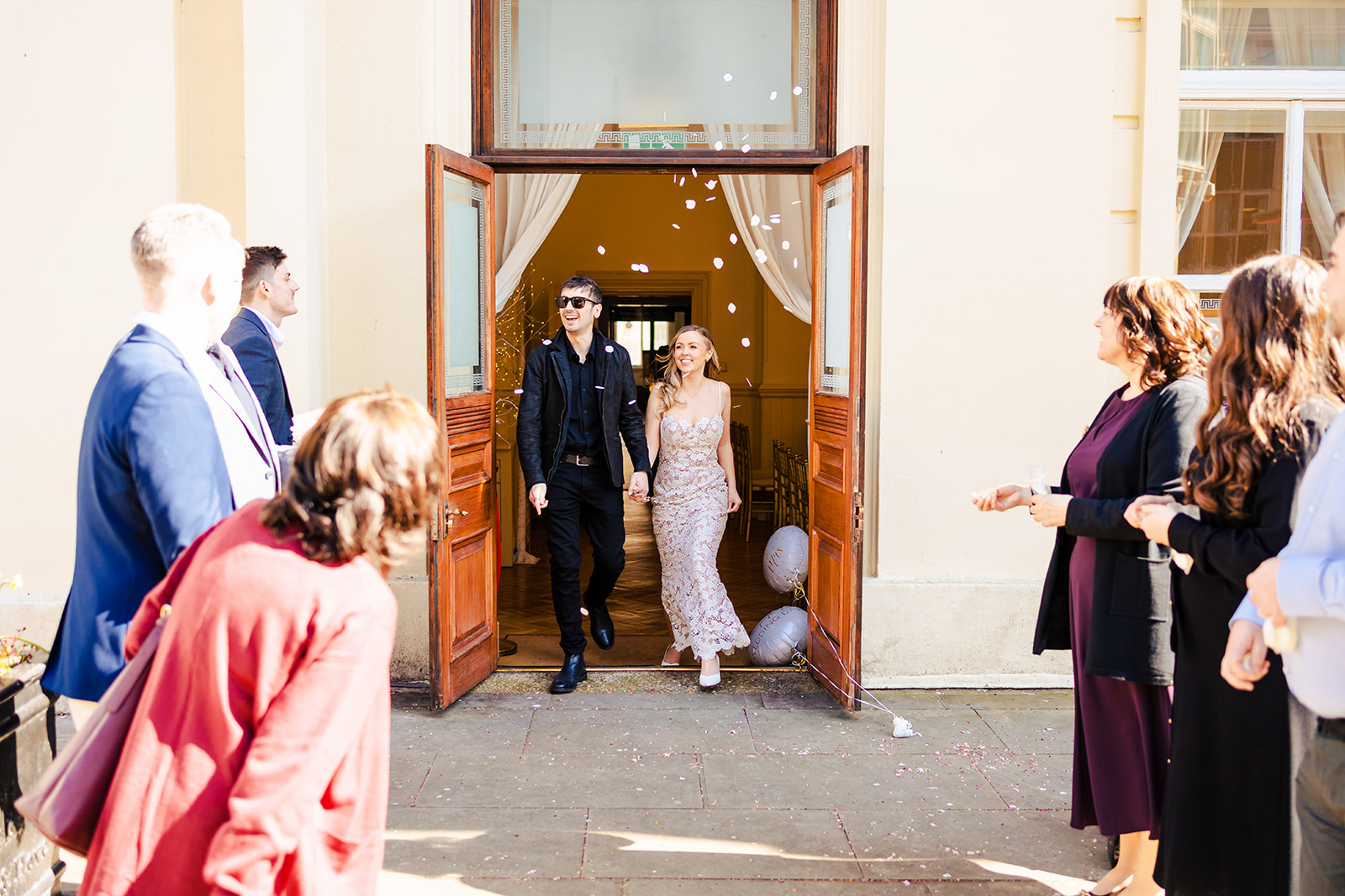 A bride and groom standing on the stairs of a building.
