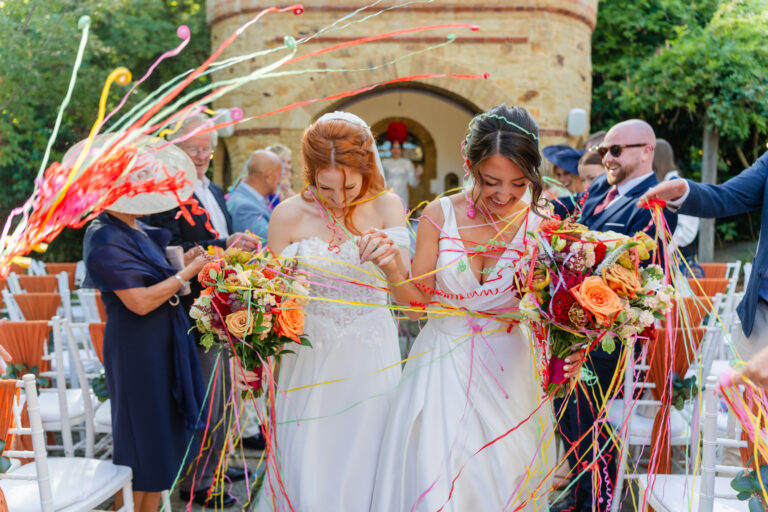 Brides laughing in a shower of confetti streamers at The Ravenswood