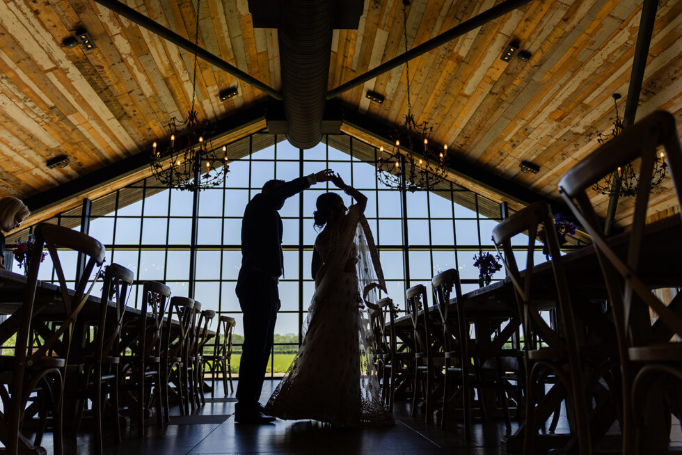 Daksha and Mark dancing in silhouette in front of the big barn windows