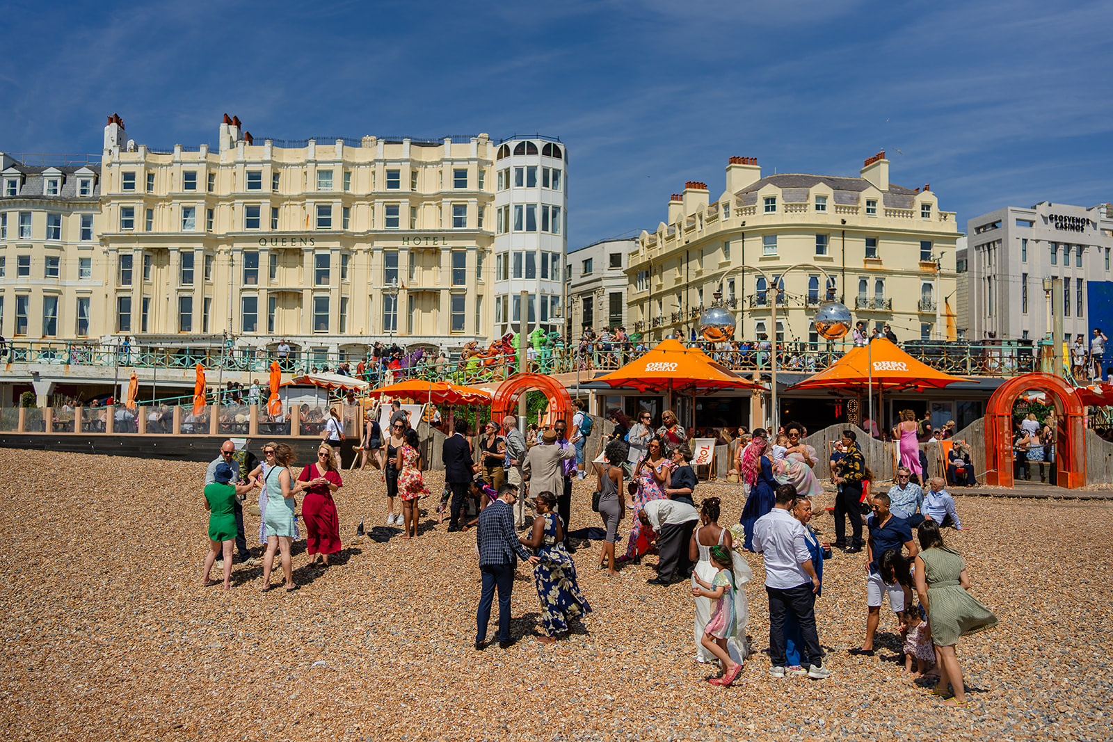 Wide shot of wedding guests drinking on Brighton beach