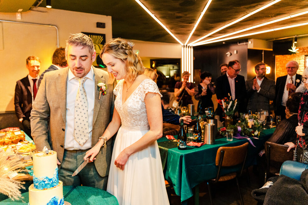 Rosie and Ross cutting the cake under the lights